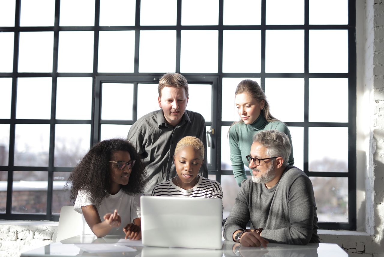 Um grupo de pessoas reunidas olhando juntas para a tela de um notebook